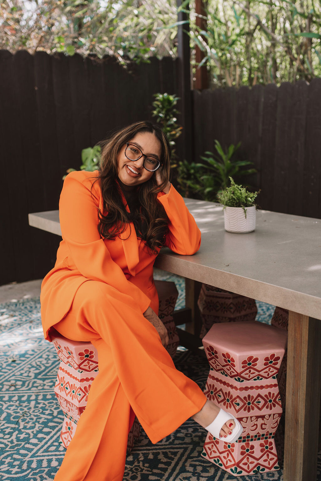 Sheyna Patel seated outside in an orange suit